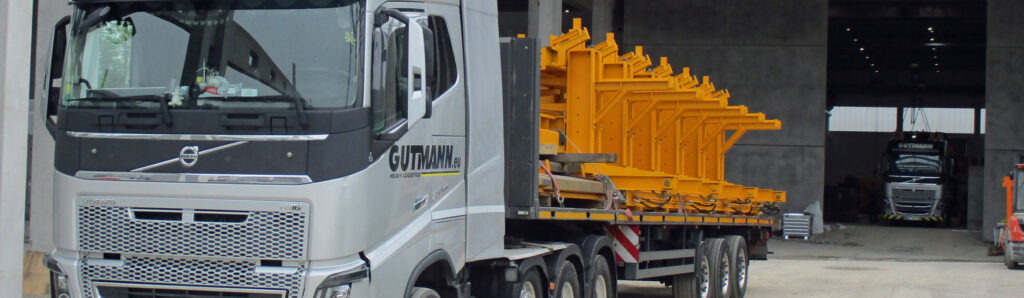 Lkw mit geladenen gelben Stahl‑ und Schalungselementen