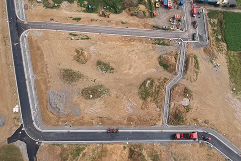 Luftaufnahme eines neu angelegten Straßenverlaufs mit Kreuzungen und angrenzenden Bauflächen.