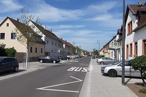 Straßenansicht in einem Wohngebiet mit parkenden Autos, Wohnbebauung und Gehwegen