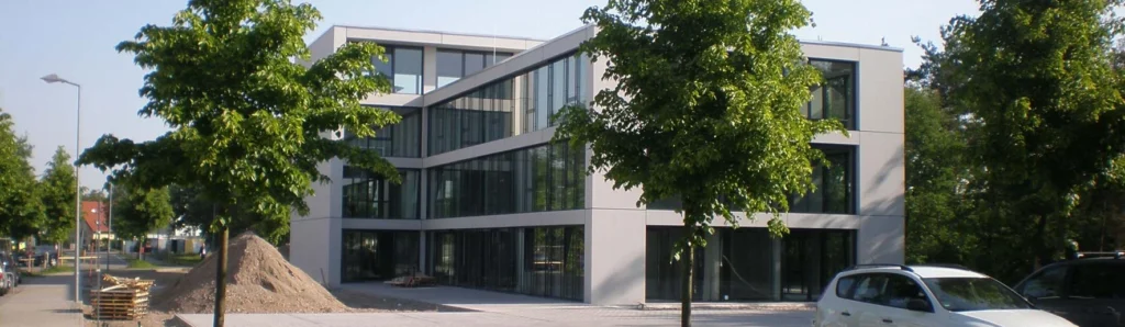 Dreigeschossiges Bürogebäude mit heller Fassade und großflächiger Glasfront