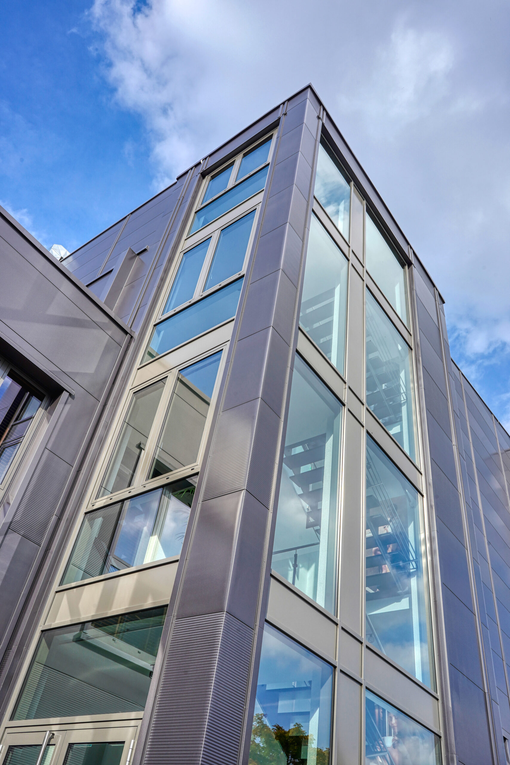 Eckansicht eines mehrgeschossigen Bürogebäudes mit Glasfassade und Metallverkleidung.